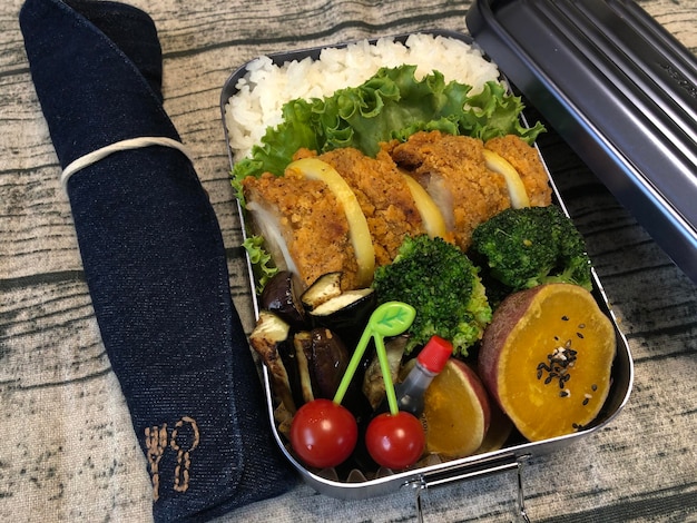 A close-up photo showcasing a bento box filled with vibrant and healthy lunch options for kids: compartments containing a mini whole-wheat pita bread pizza with colorful veggies, a side of grapes and blueberries, cheese cubes, and a small container of hummus with carrot sticks, highlighting appealing presentation and variety.