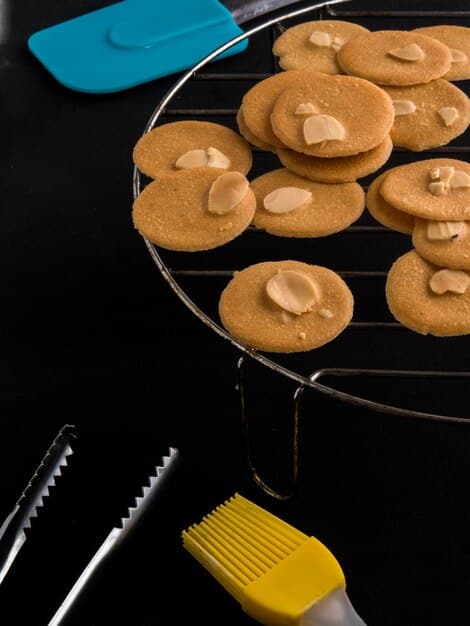 Close-up shot of several peanut butter cookies cooling on a wire rack, with a fork resting beside them, highlighting the criss-cross pattern and golden-brown color.