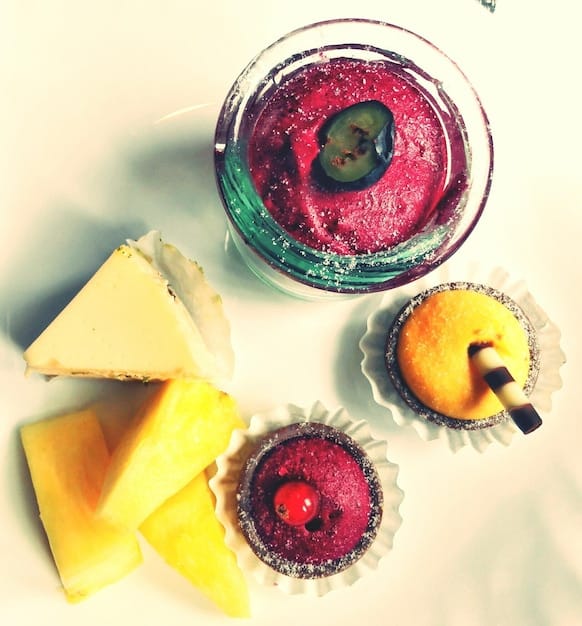 A close-up shot of various colorful fruits (berries, bananas, spinach) and smoothie ingredients arranged neatly on a kitchen countertop, with a blender in the background, ready to be used. The scene is well-lit, emphasizing the freshness and variety of the ingredients.