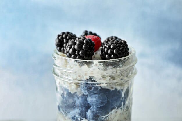 A close-up shot of overnight oats in a clear mason jar, layered with fresh berries, chia seeds, and a drizzle of honey, highlighting the vibrant colors and textures of the healthy breakfast ingredients.