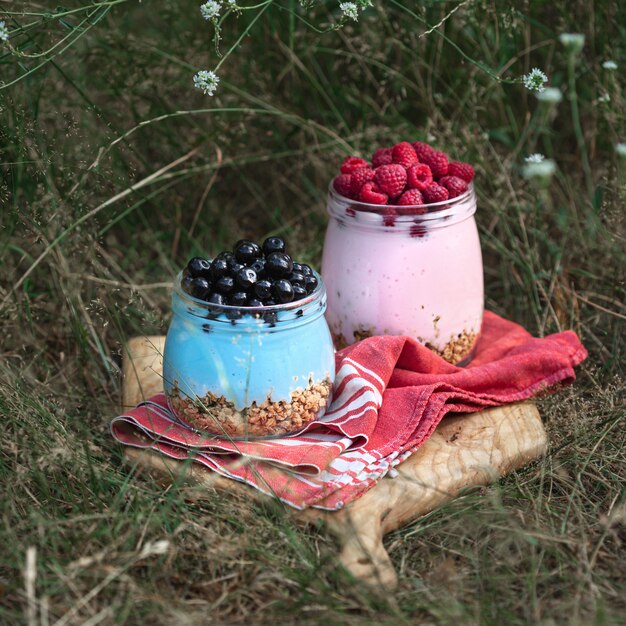 A colorful display of various mason jar parfaits, each layered with granola, yogurt, and different fruits like strawberries, blueberries, and kiwi, showcased on a wooden table with natural lighting.