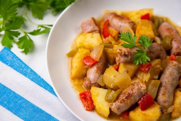 A close-up shot of a sheet pan dinner with sausage, potatoes, bell peppers, and onions, seasoned with herbs and spices. The focus is on the caramelized texture and vibrant colors of the roasted vegetables and sausage.