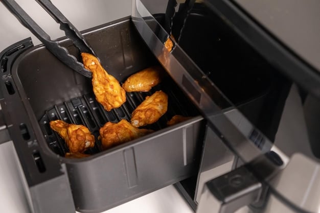 An image showing the inside of an air fryer basket with evenly spaced chicken wings, golden brown and crispy. The background shows a hand using tongs to carefully flip the wings, ensuring even cooking.