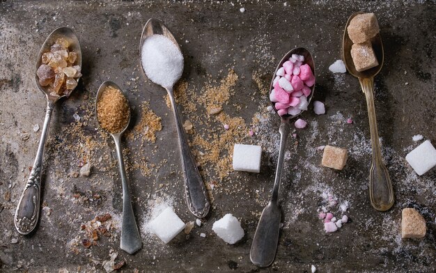 A close-up shot of measuring cups and spoons filled with different amounts of sugar, showcasing a visual representation of gradual sugar reduction in baking. Focus on the precision of measurements and the contrasting amounts.