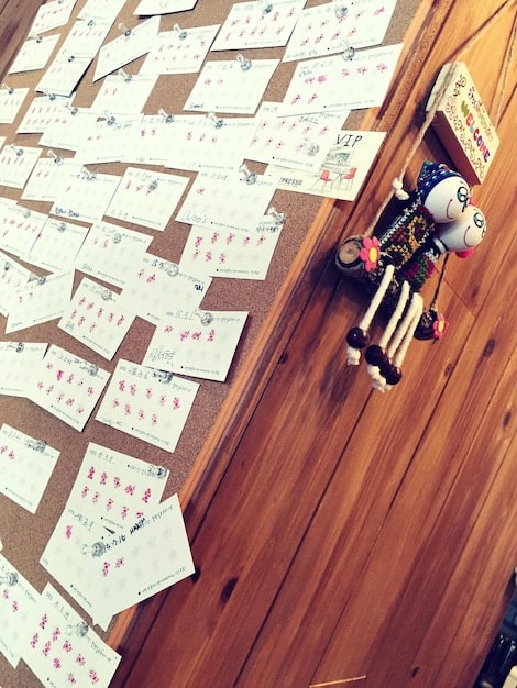 A bird's-eye view of a Codenames game in progress, with a grid of word cards spread out on the table. Two teams of players are huddled around the table, intently discussing the clues provided by their spymasters. The lighting is bright and even, showcasing the game's vibrant colors and engaging design.