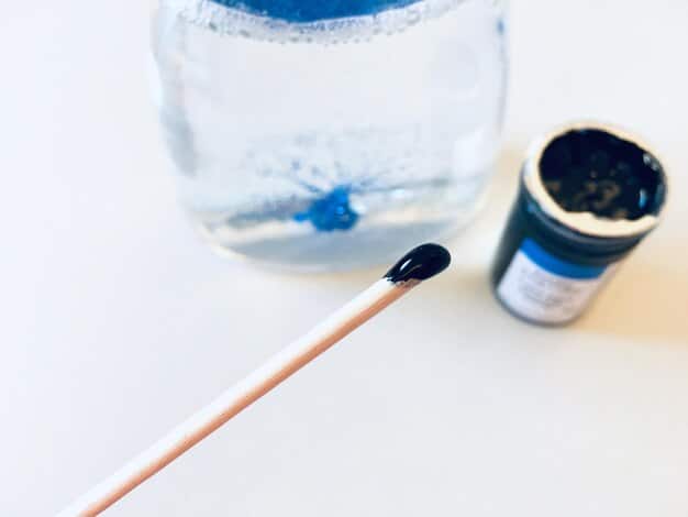 Close-up of activated charcoal being poured into a clean glass container, highlighting its use in removing impurities from water in a DIY filter.