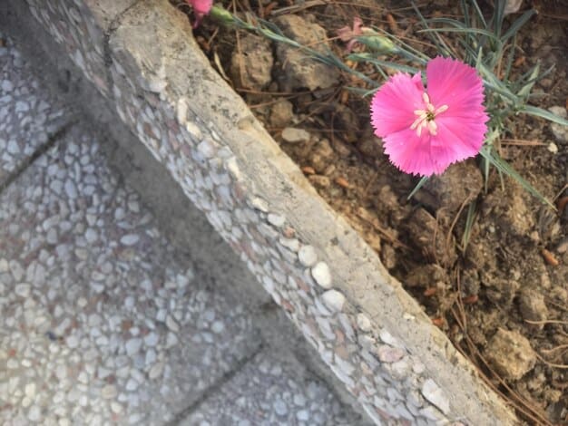 A close-up showing the base of a raised garden bed with visible drainage layers consisting of gravel, landscape fabric, and well-draining soil mix. The image focuses on the layers and their textures.