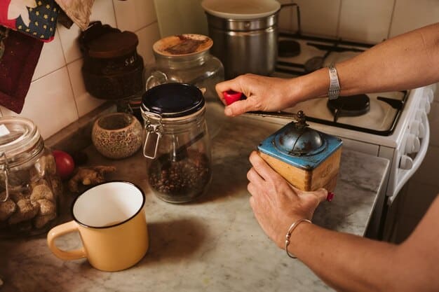 A close-up shot of a person sorting kitchen scraps (vegetable peels, coffee grounds) into a small, indoor compost pail with a charcoal filter. The setting is a bright, modern kitchen.