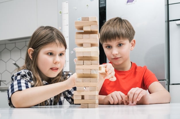 Two young children are building a tall tower out of blocks. They are concentrating intently, working together to balance the blocks and prevent the tower from falling. The room is filled with natural light, creating a playful and engaging atmosphere.