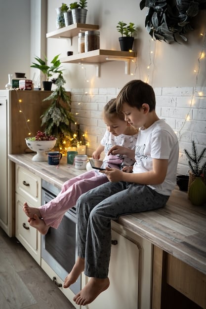 A photograph showcasing a parent and child sitting together at a kitchen table. The child is using a colorful calculator, while the parent is pointing to a handwritten budget sheet. The setting conveys a warm, educational environment where financial skills are being taught and practiced interactively.