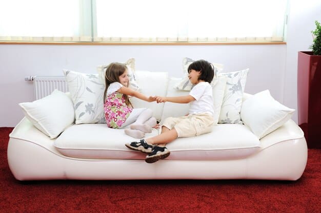 A parent and child having a comfortable conversation on a couch, both smiling and engaged.