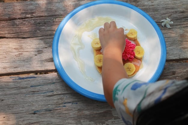 A close-up shot of a child's plate during a family meal, showcasing a balanced portion of colorful vegetables, a piece of grilled chicken, and a small serving of whole-grain rice. The image emphasizes the nutritional variety and healthy choices available during family mealtime.