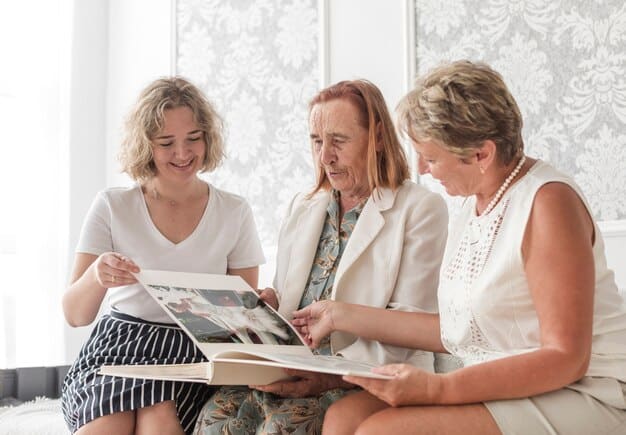 Three generations of women in a family are sitting together in a living room, looking at old photographs and documents, laughing and talking.