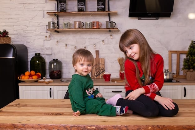 Two mothers sitting at a kitchen table, smiling and talking while their toddlers play together on the floor nearby. The scene conveys a sense of partnership and shared responsibility.