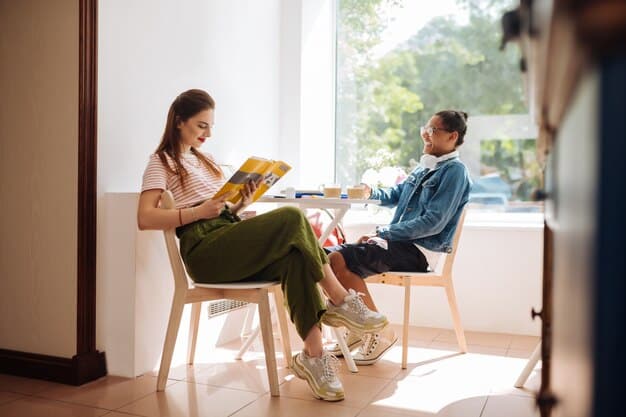 A parent and child sitting together in a daycare waiting area, reading a book and looking relaxed, with daycare staff visible in the background.